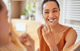 woman smiling while brushing her teeth