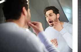 Patient in Beverly checking their new dental implants in the mirror