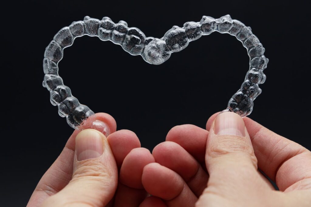 Two clear aligners being held in the shape of a heart